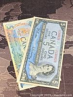 Photo showing two Canadian five dollar banknotes, one from 1954 with a blue-grey design and one from 1979 with a modern design.