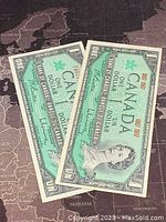 Two 1967 Canadian one dollar banknotes displayed fanned out showing front side with Queen Elizabeth II portrait and green tint.