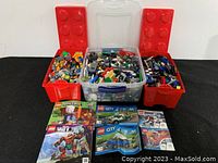 Front view showing three plastic containers filled with assorted Lego pieces and six instruction manuals laid out in front.