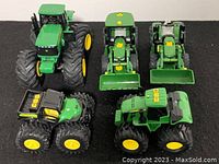 Overview of all five John Deere toy vehicles on a black surface showing various models of tractors and an off-road vehicle.