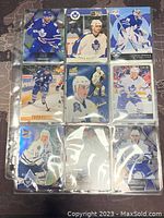 Photo showing nine Toronto Maple Leafs hockey cards featuring players in action and portraits in blue uniforms, stored in plastic sleeves.