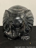 Front view of large black elephant sculpture showing detailed trunk, ears, and face.
