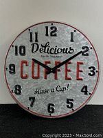 Full view of the metal wall clock showing clock face, numbers, and coffee-related text.
