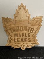 Front view of wooden sign shaped like a maple leaf with 'Toronto Maple Leafs' text.