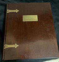 Closed top view of dark wood rectangular box resembling a memory book with brass accents on a black background.