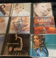 First photo showing eight CD jewel cases on a surface, recognizable titles include Madonna, Ricky Martin, Faith Hill, and The Kinleys.