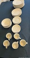 Photo showing full set of Johnson Brothers Athena model dinnerware including dinner plates, salad plates, bread and butter plates, bowls, saucers, and cups arranged on a blue surface.