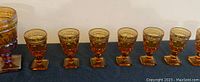 Three large amber glass chalices with wide bowls and sturdy square bases in a row