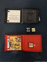 Open Mario vs Donkey Kong Mini-Land Mayhem game case showing manual and Mario vs Donkey Kong game cartridge inside, plus Phineas and Ferb and SpongeBob cartridges outside case.