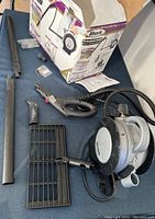 Shark Professional steam cleaner main unit with hose, steam gun handle, two extension tubes, cleaning accessories, user manual, and box displayed on couch.