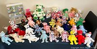Large assortment of multiple TY Beanie Babies plush toys lined up on a flat surface, with various colors and styles visible, all having attached tags.