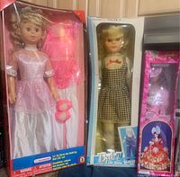 Photo showing three boxed dolls including 32" Kid Connection walking doll, Daisy walking doll, and porcelain collector doll with red and white outfit.