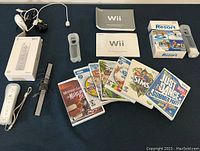 Full overview of all items including Wii Remotes, Sensor Bar, multiple Wii game cases, manuals, original Wii Remote box, and accessories.