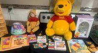 Full lot displayed including large Pooh plush, vintage-style Pooh doll, boxed clock, tree base figurine, perpetual calendar, books, puzzles, and hat.