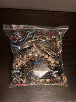 Large clear zip-seal freezer bag filled with assorted costume jewelry pieces predominantly necklaces and bracelets in various materials and colors.