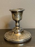 Front view of tarnished sterling silver candlestick with engraved base design