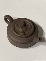 Top side view of the round purple clay teapot with relief water buffalo and bird on the lid.