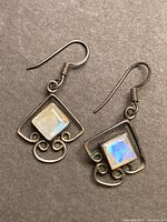 Front view of the sterling silver earrings showing square moonstone gemstones and artistic silver frame.