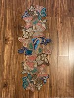 Front view of vintage hand beaded butterfly table runner showing colorful butterflies densely arranged with intricate beadwork on fabric backing.