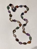 Full length view of the necklace showing various colored gemstones linked in a chain.