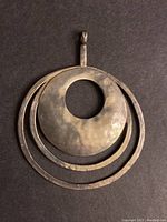 Front view of large circular sterling silver pendant with concentric ring design and hammered texture.
