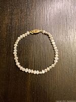 Full view of white freshwater pearl bracelet laid flat showing clasp and pearls.