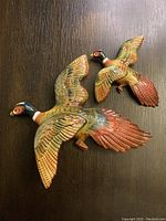 Top view of two porcelain pheasant wall hangings showing detailed coloration and feather design.