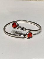 Front view showing red stones and intricate silver detailing on open ends of the bangle bracelet.