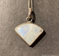 Close-up of fan-shaped moonstone pendant set in sterling silver with faint blue adularescence visible.