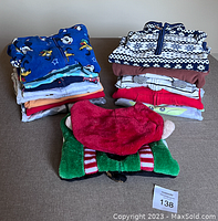 Photo showing folded fleece and cotton sleepers and jumpsuits in various prints and colors including holiday elf theme.