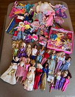 Overall view of all dolls, clothing, and carrying bag spread out on surface.