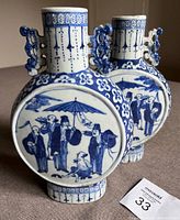 Front view of both vases side by side showing roundel figural scenes and floral-border decoration