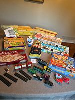 Full lot overview showing board games boxed and toy trains with track pieces on a table.