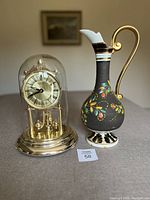 Photo showing both clock and decorative jug side by side on a table with neutral background.