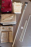 Curtains and white metal curtain rods with accessories laid out on a floor showing sizes and condition