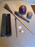 Photo showing collection of Harry Potter-themed accessories including broomstick, two quidditch balls, wooden bat, wand in box and keychain.