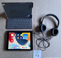 Apple iPad Air 2, keyboard case, and Klipsch headphones photo showing all items together.