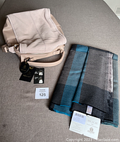 Moda Luxe leather bag with tags next to folded MA.AL.BI. wool shawl showing fabric pattern and tags.