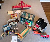 Wide view of entire Brio train toy set arranged on a beige carpet. Includes bridges, buildings, vehicles, rock formations, and figures.