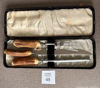 Vintage set of three stainless steel carving tools with antler-style handles, in black case lined with satin, showing wear and one broken case clasp