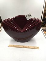 Front view of glossy maroon Art Deco style ceramic vase alongside a ruler for scale measurement showing approximately 15 inches width.