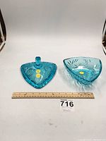 Wide photo showing two turquoise blue triangular pressed glass dishes side by side, with a ruler for scale