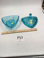 Blue glass triangular dish and matching lid placed side by side with a ruler showing size.