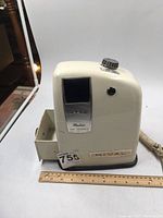 Front angled side view of vintage Rival electric ice crusher, showing cream color body, control knob, and pull-out drawer.
