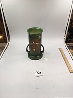 Green Roseville Showery vase shown from full front with side handles and raised floral decoration.