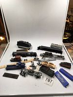 Full view of model train pieces scattered on white backdrop including engines, cars, parts and accessories
