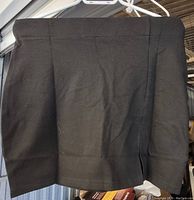 Front view of black stretch skirt showing material and design details including side slit and seam.