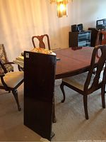 Wood dining table with three dining chairs and a captain's chair, showing the table surface and chair details.