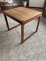 Photo showing the wood veneer end table from a side angle, illustrating light sanding on the surface and the open frame legs
