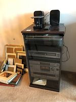 Stereo system components including turntable, CD changer, receiver, cassette deck in black cabinet with glass door